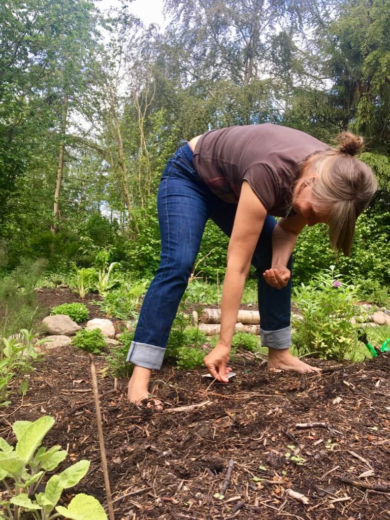 Anja Dalby: Gør du en forskel? Anja i haven ved at plante frø. Står i bare fødder i et bed.
